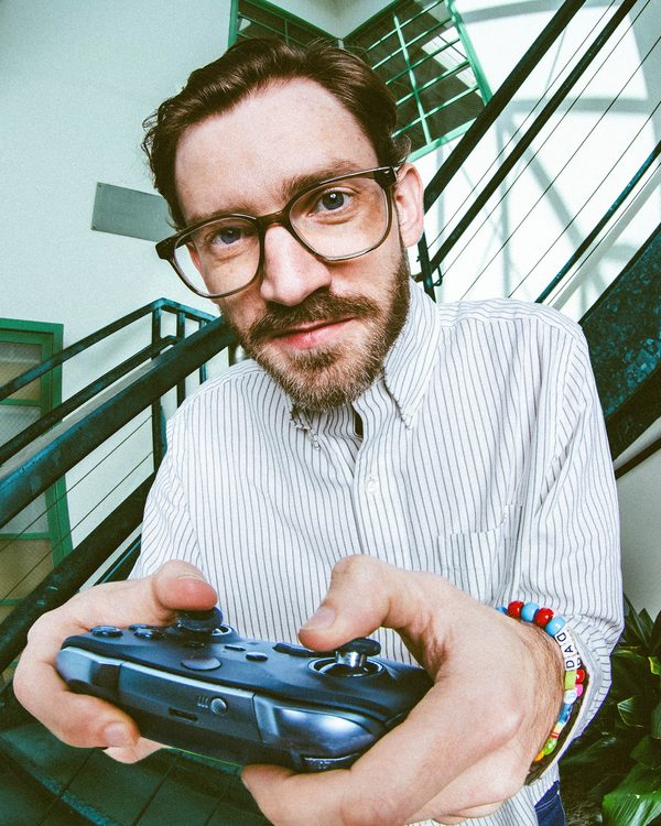 Mike Dyer holding a game controller toward the camera